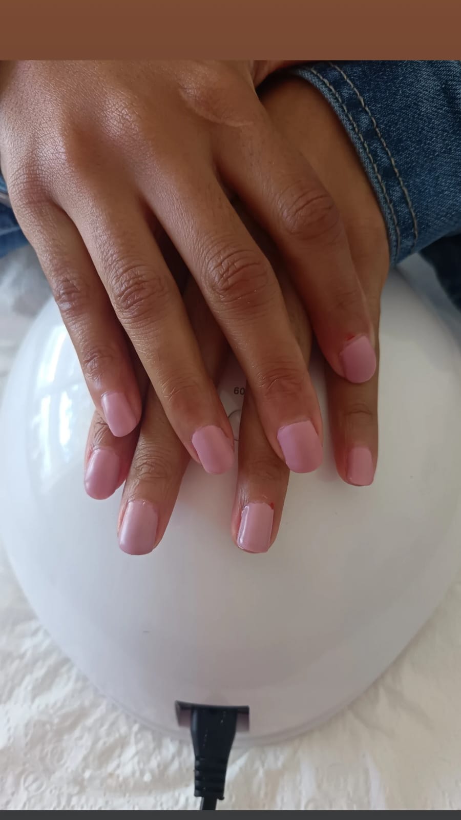 Blush pink gel nails on a manicure lamp